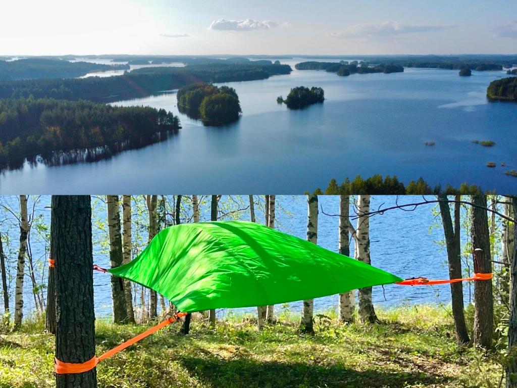 a green tent on top of a hill overlooking a lake at Alaska Tree Tents Linnansaari in Savonlinna