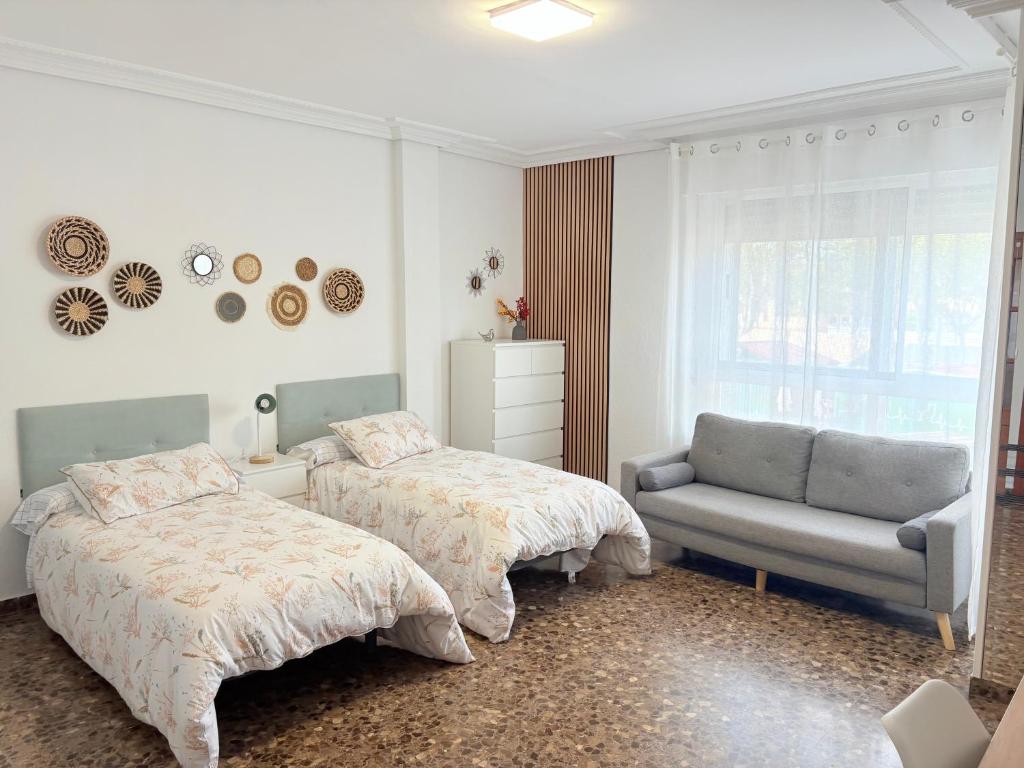 um quarto com duas camas, uma cadeira e uma janela em Feria by Birdie JUSTO FRENTE A LA FERIA em Albacete