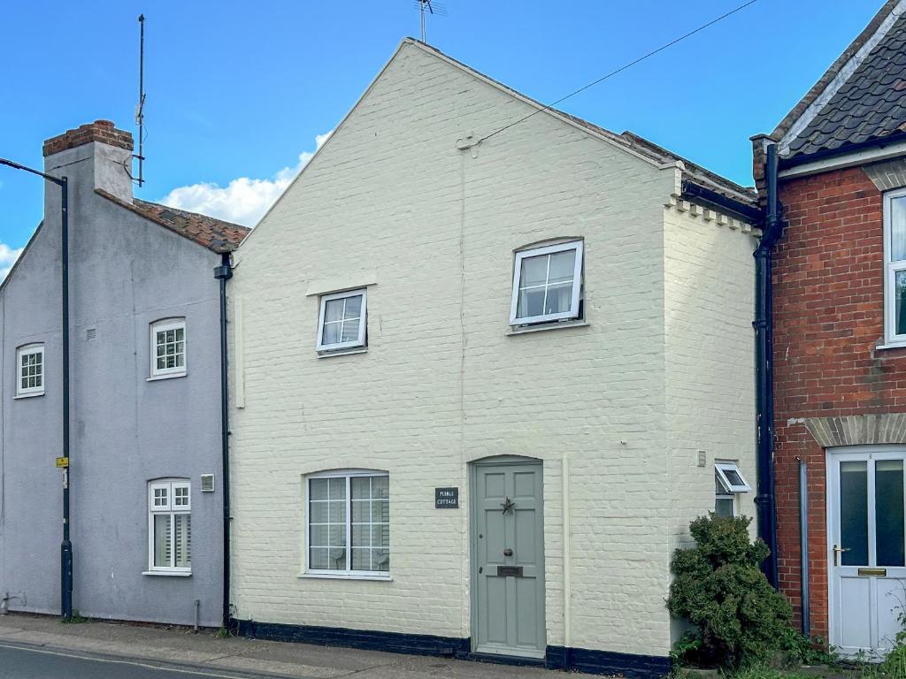 ein weißes Haus mit einer weißen Tür in einer Straße in der Unterkunft Pebble Cottage in Aldeburgh