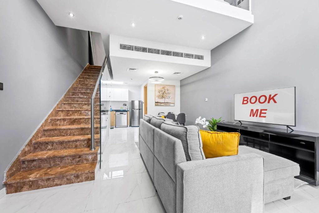 un salon avec un canapé et un panneau « Réservez-moi » dans l'établissement StayShort - Cozy 1BR Townhouse loft style located in Rukan Community, à Nadd Shubayḩ