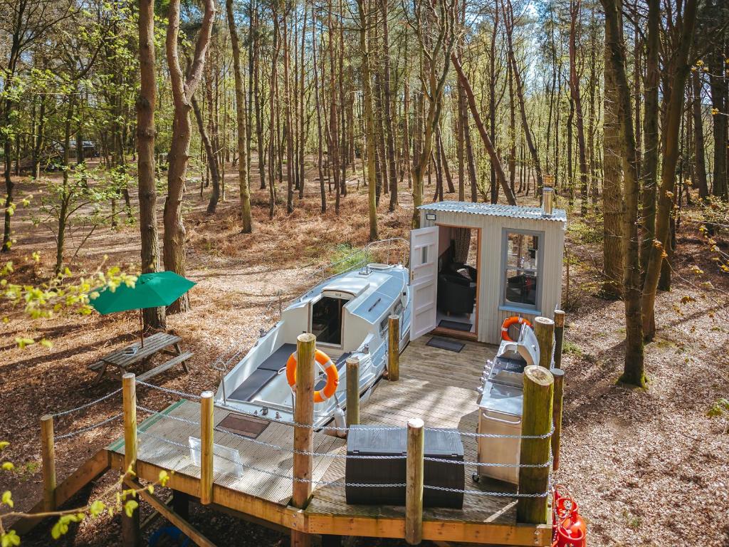 an rv parked in the woods with a porch at Chere Amie-Qu7616 in Melton Constable