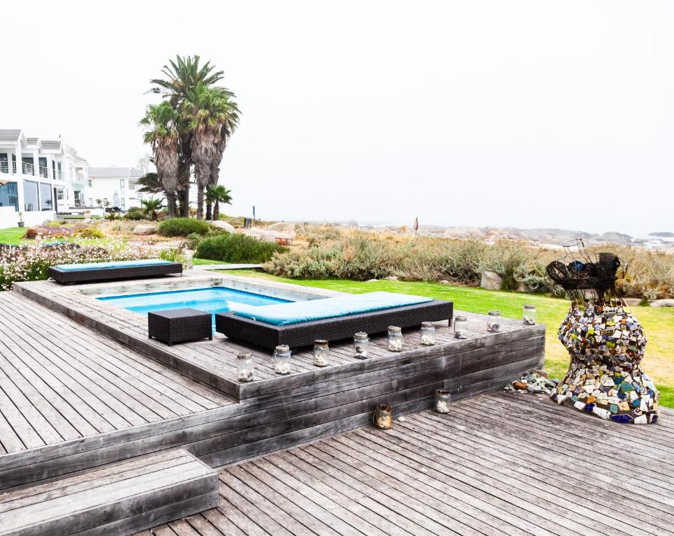 een zwembad op een houten terras met een beeld bij SableChateau Beachfront Guesthouse in Stompneusbaai