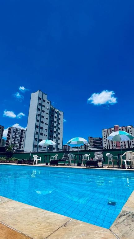 ein Schwimmbad mit Liegestühlen und Sonnenschirmen in einer Stadt in der Unterkunft Hotel Lux in Poços de Caldas
