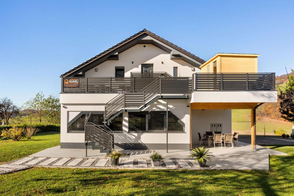 a white house with stairs and a balcony at Apartmaji Kunej pod Gradom in Podsreda