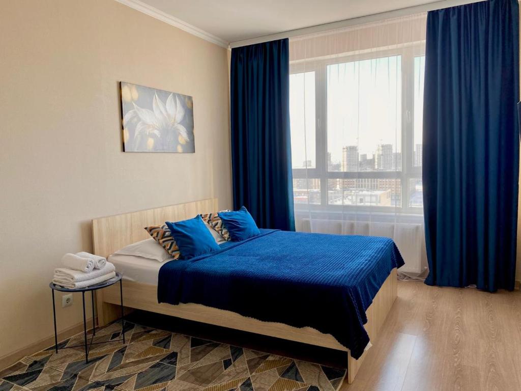 2х комнатные и Однокомнатные квартиры на Туране في Taldykolʼ: غرفة نوم بسرير وملاءات زرقاء ونافذة