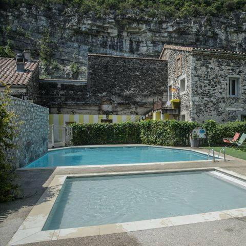 a large blue swimming pool in front of a building at Oh! Campings - Medrose Camping Ardèche in Saint-Thomé