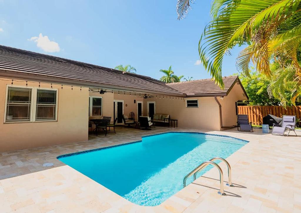 a swimming pool in front of a house at Poolside Miami Paradise with BBQ & Outdoor Lounge in Country Walk