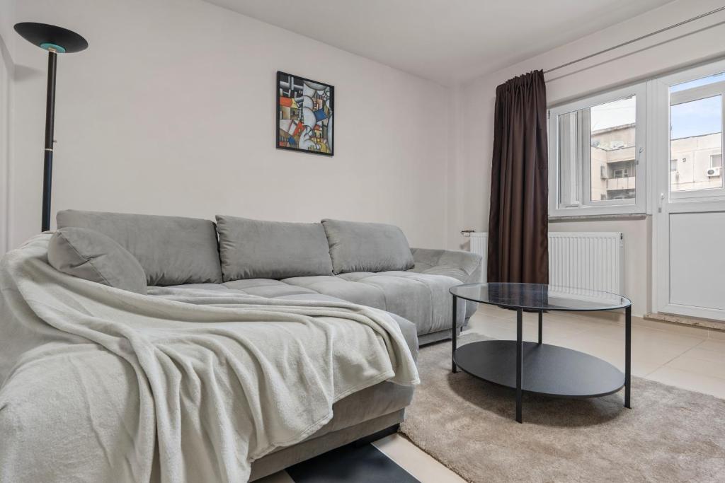 een woonkamer met een bank en een glazen tafel bij Modern 1BR Retreat Coffee & Peace in Boekarest