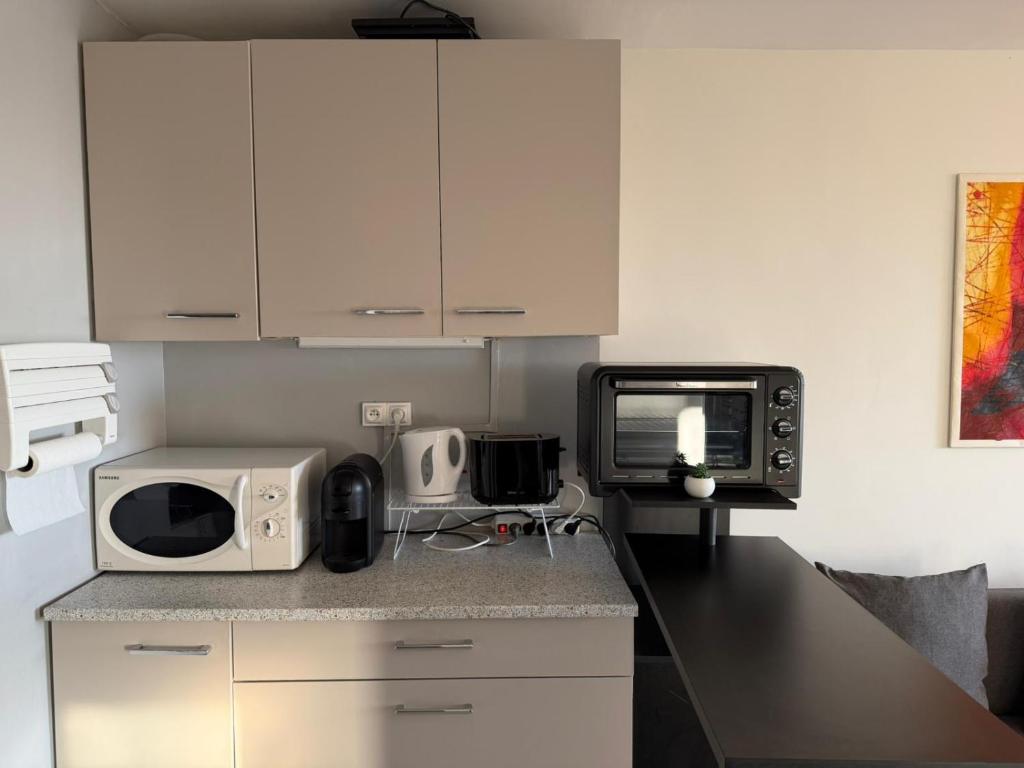 eine Küche mit einer Arbeitsplatte mit Mikrowelle in der Unterkunft River City - Joli 2 pièces, étage élevé, vue sur port et mer, calme et proche des plages in Mauguio