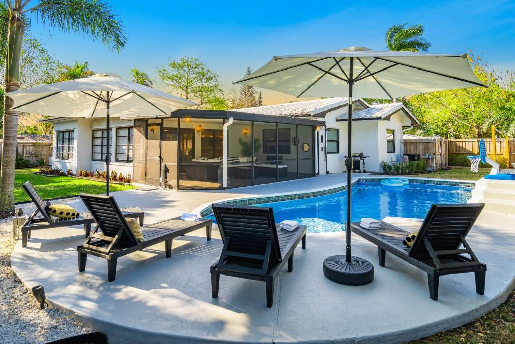 ポンパノビーチにあるVilla Heated Pool, Arcade games 5 min Beachのプールサイドのパティオ(椅子、パラソル付)
