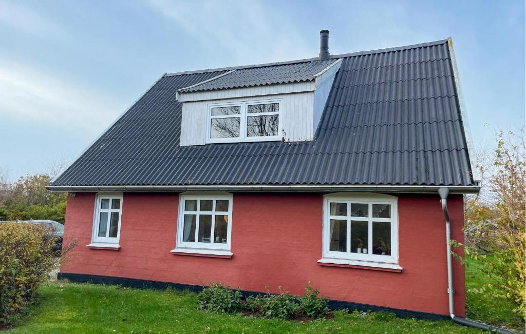 a red house with a black roof and two windows at Awesome Home In Skagen With Wifi in Hulsig