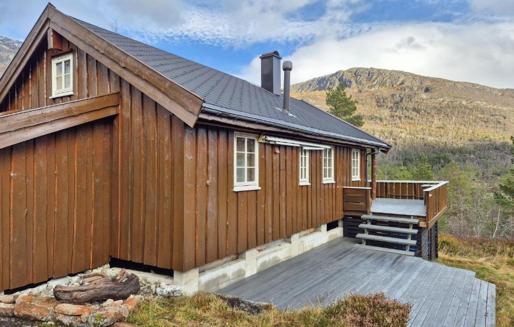 een houten huis met een terras en bergen op de achtergrond bij Amazing Home In Skare With Sauna in Seljestad
