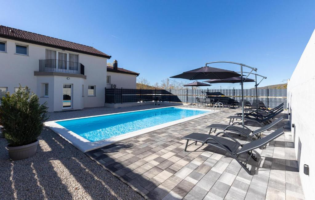 een zwembad met stoelen en een parasol naast een huis bij Awesome Home In Imotski in Lokvičič