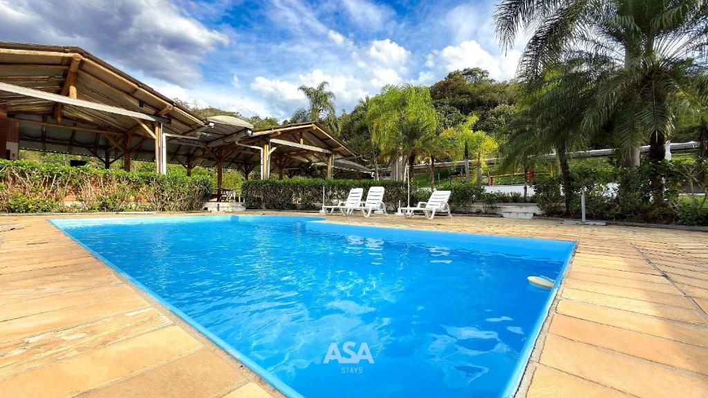 une piscine avec deux chaises et une maison dans l'établissement ASA | Sítio Vô Tontini | Natureza | Quadra | Pisc., à Gaspar