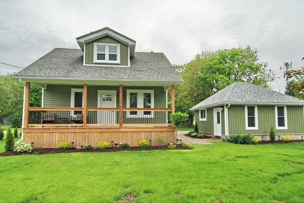 a green house with a large deck on a yard at Shores of Erie Guest House in Essex