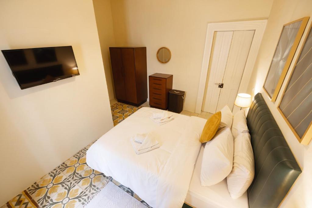 a bedroom with a white bed and a television at Bormla 1 in Cospicua