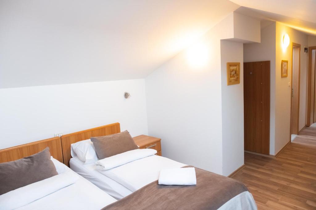 twee bedden in een kamer met witte muren en houten vloeren bij Garni Hotel Keltika in Izola