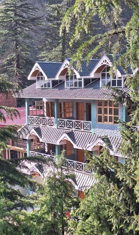 ein großes Resortgebäude mit Bäumen im Vordergrund in der Unterkunft Khili's Abode in Harsil