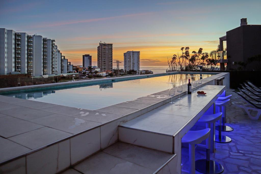 a swimming pool with blue stools next to a building at Nirvana - Luxury Villa with heated pool in Playa Paraiso