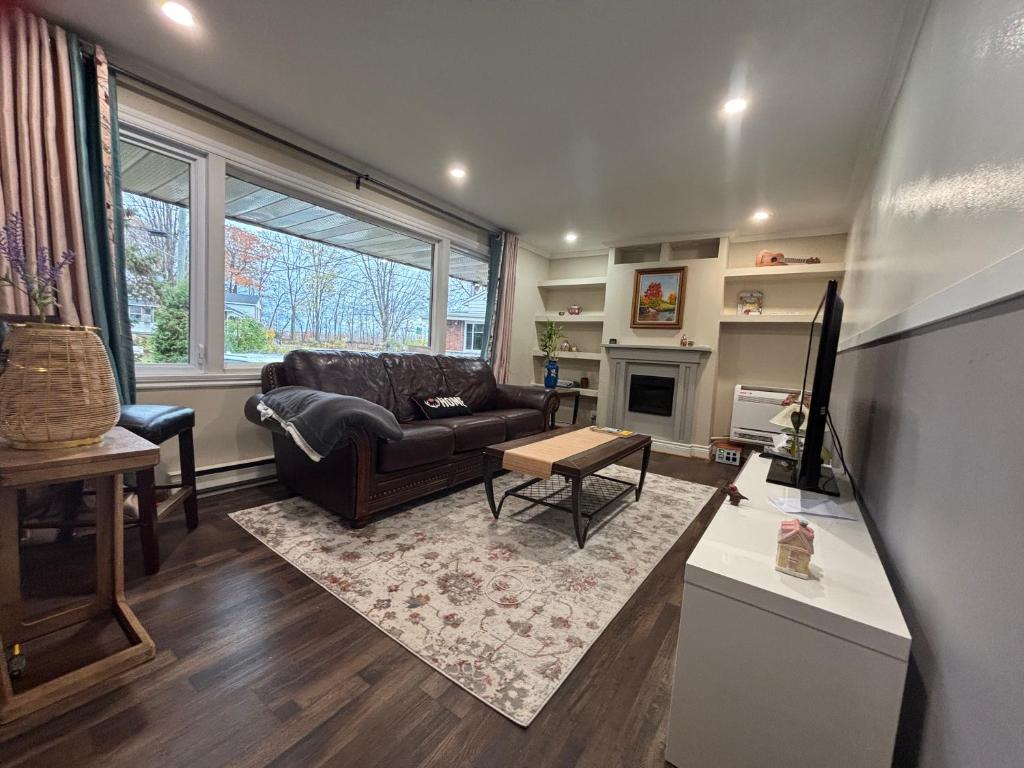 uma sala de estar com um sofá e uma mesa em Entire floor in a Spacious bungalow ensuite close to beach and train em Pincourt