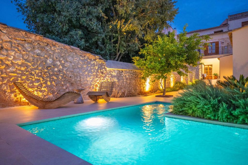a swimming pool in a yard with a stone wall at Cas Català in Sineu