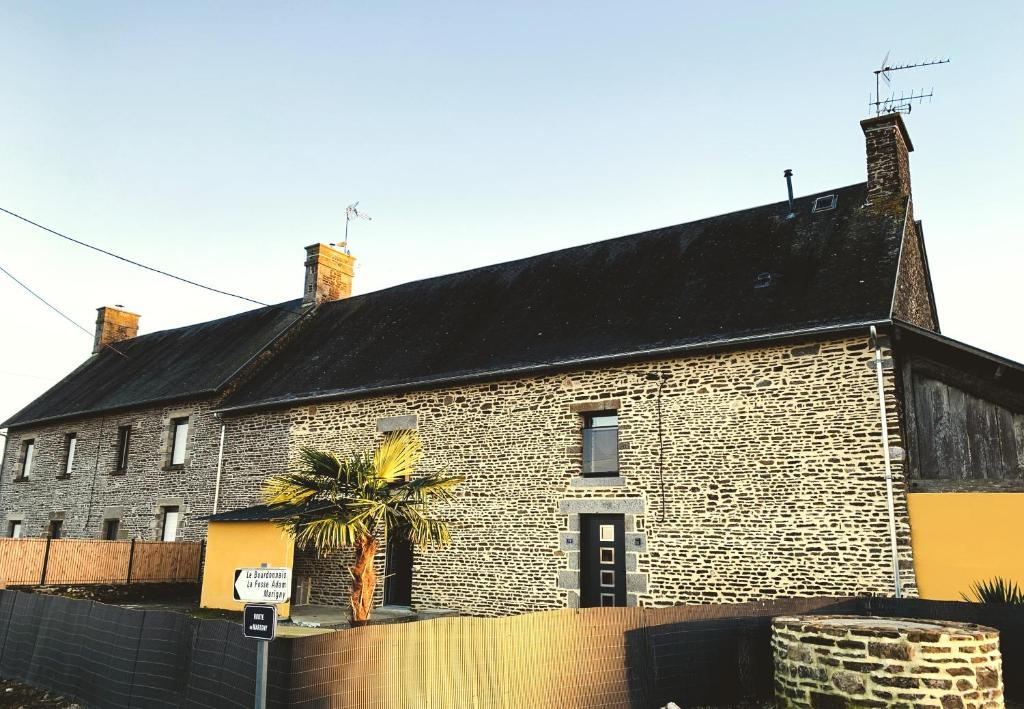 a brick building with a palm tree in front of it at Le Gîte du Plessis Montanel à 25 mn du Mont Saint-Michel in Montanel