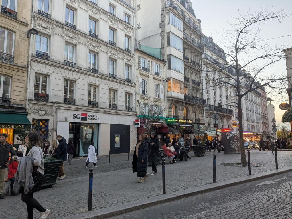 a group of people walking down a street with buildings at Cosy renovated little nest in historic MONTMARTRE in Paris