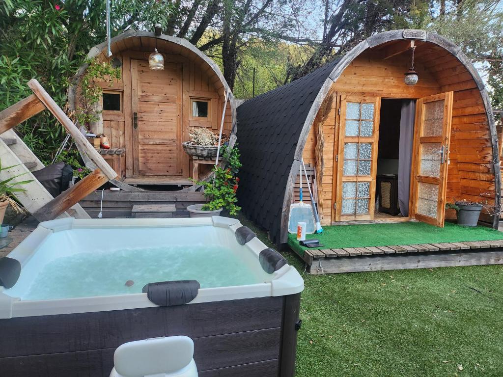 eine große Wanne in einem Hof neben einem Hobbithaus in der Unterkunft Cabane Sauna & Jacuzzi Hiver in Vaccili