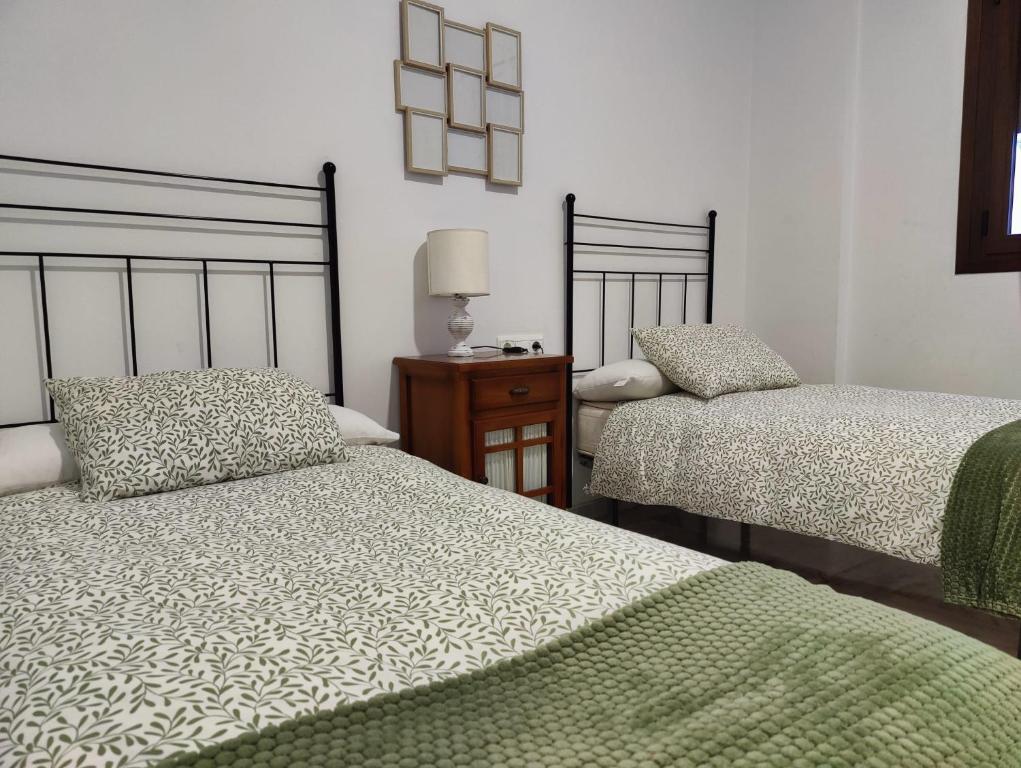 ein Schlafzimmer mit zwei Betten und einem Tisch mit Lampe in der Unterkunft Apartamentos La Bola 94 in Ronda