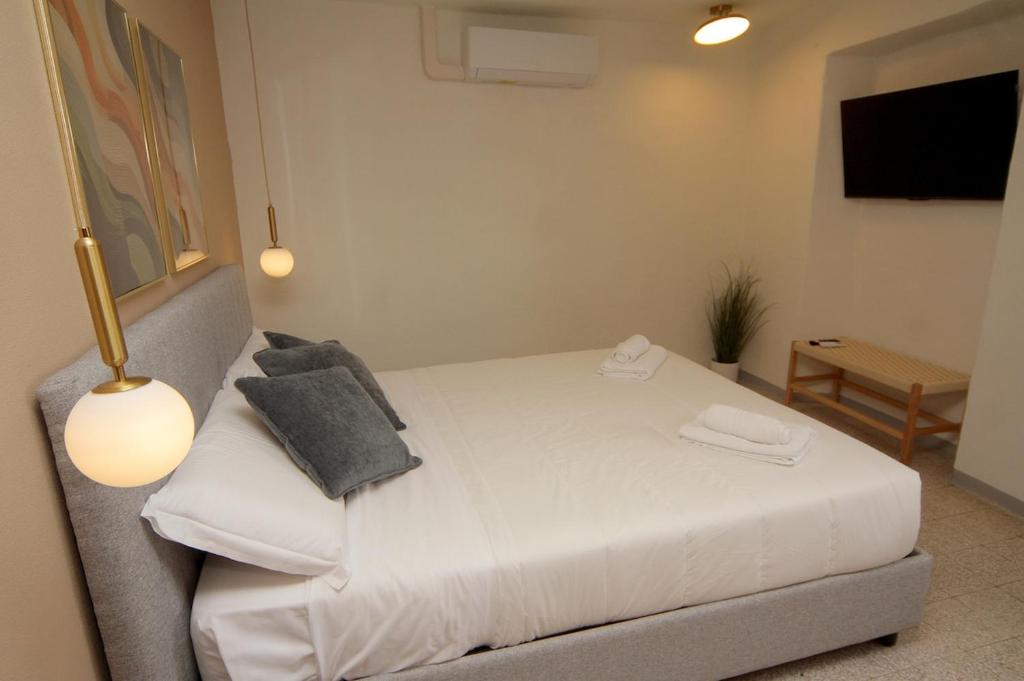 a bedroom with a white bed and a television at Casa Piazzetta - Lake Como WiFi & A-C in Dorio