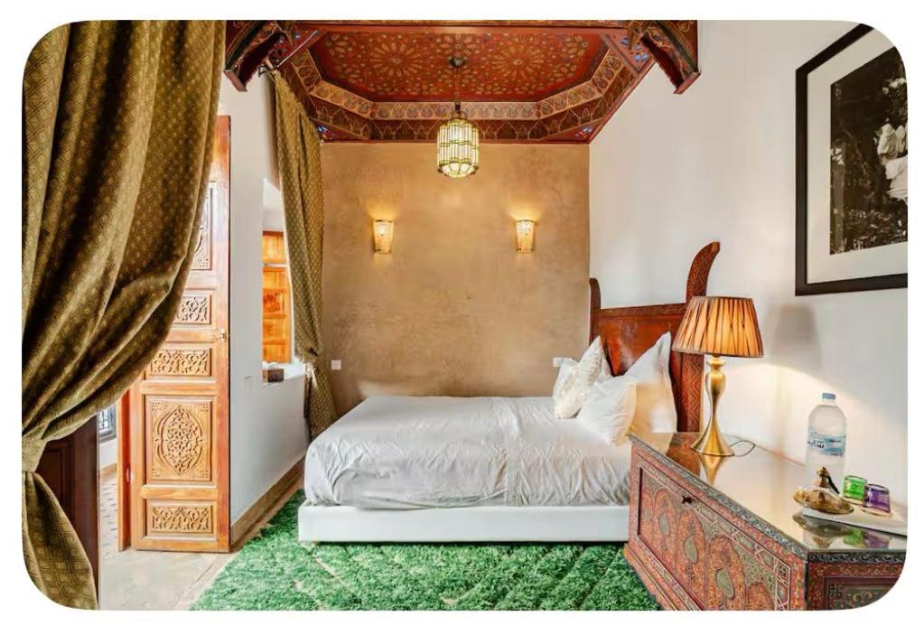een slaapkamer met een bed en een tafel met een lamp bij Riad Serendip in Marrakesh