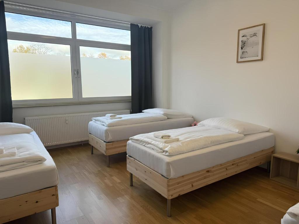 drei Betten in einem Zimmer mit Fenster in der Unterkunft T&K Apartments - Comfortable 4 and 5 room Apartments - 20min Fair Messe CGN in Overath