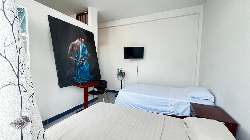 プエルト・マルドナードにあるLa Terraza Hostelのベッドが2つあり、壁に絵が飾られている部屋