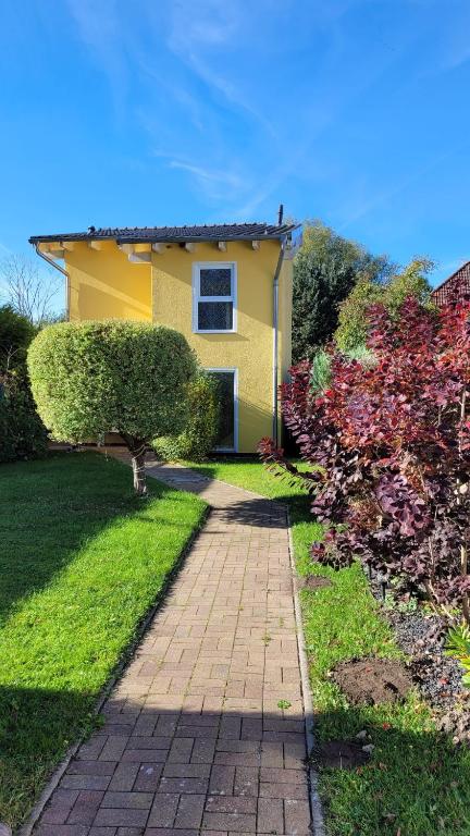 a yellow house with a brick walkway in a yard at Ferienhaus an der Brunnenaue 4 Sterne, E-Ladestation am Haus, Wlan, Netflix, Garten in Sagard
