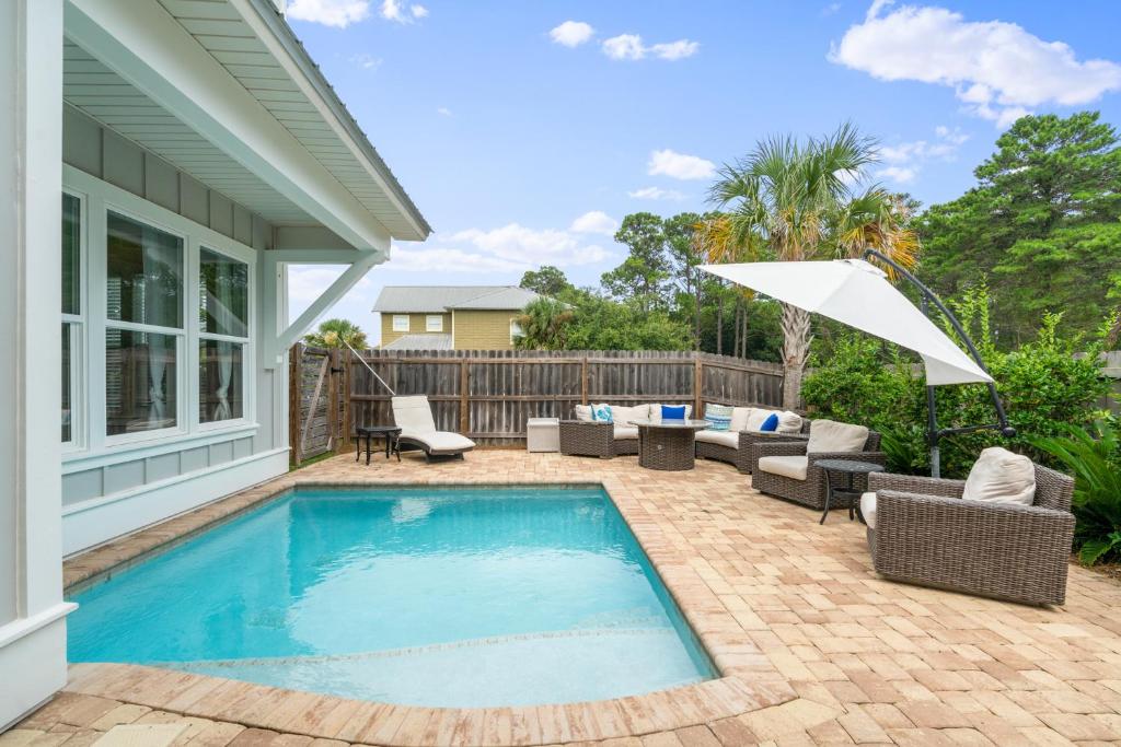 einen Pool mit Stühlen und einem Sonnenschirm neben einem Haus in der Unterkunft Oceans 11 Oasis at Gulf Place in Santa Rosa Beach