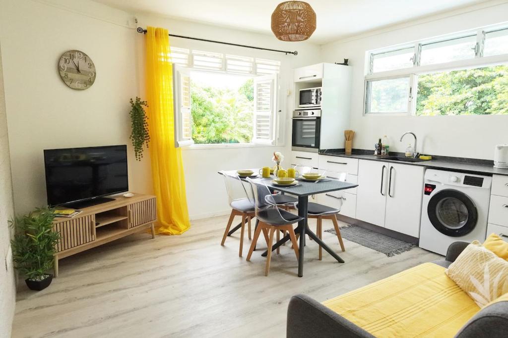 a kitchen and living room with a table and a tv at Milo Cosy T2 climatisé à 2 mn de la plage du 972 in Sainte-Luce