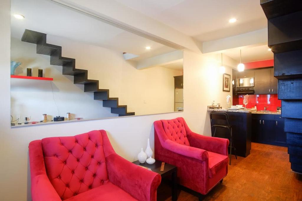ein Wohnzimmer mit zwei roten Stühlen und eine Küche in der Unterkunft Lovely and Cozy Apartment in Colonia Cañón Doña Petra