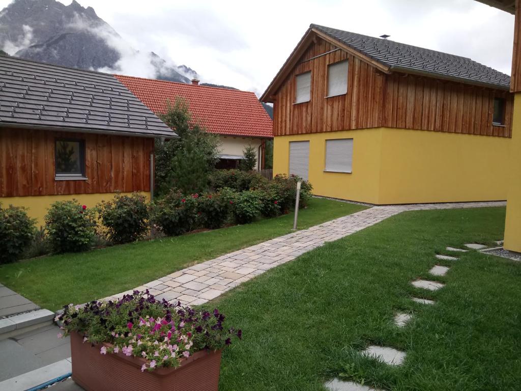 two houses in a yard with mountains in the background at Feriendorf Uorsin in Scuol