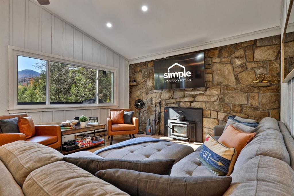 ein Wohnzimmer mit Sofas und einer Steinmauer in der Unterkunft Roaring Bear Cabin - Secluded Killington Retreat with Hot Tub and Fire Pit in Sherburne Center