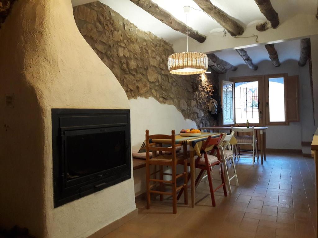 a living room with a fireplace and a table and chairs at Casa cova de Benifallet in Benifallet