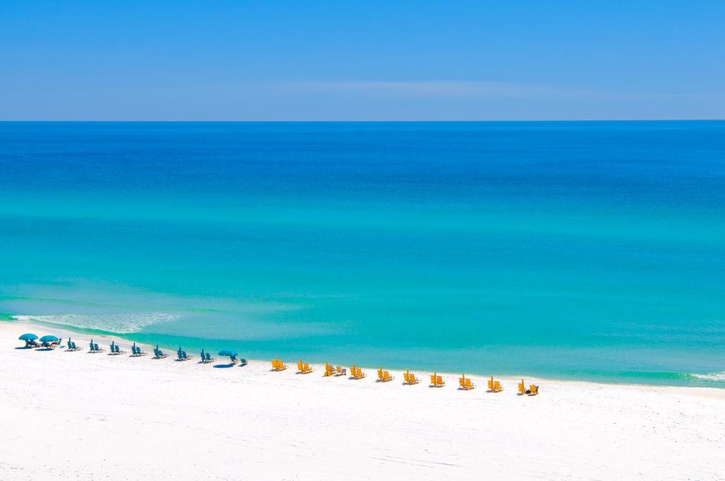 a line of chairs on a beach next to the ocean at Pilot House 507 in Destin