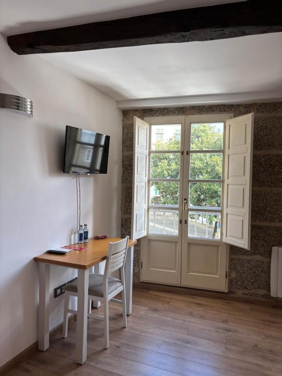 a room with a table and a tv and a window at Pension Via-Stella in Santiago de Compostela