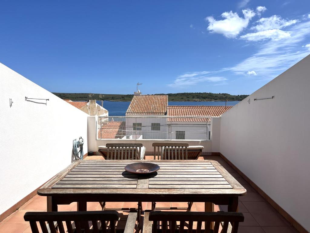a balcony with a wooden table and chairs on a roof at Riera Rossello 1 in Fornells