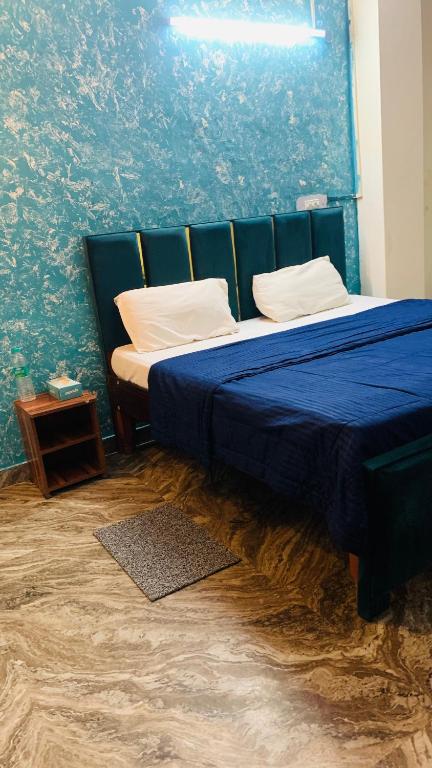 a bedroom with a bed with a blue wall at Glory hotel in Noida