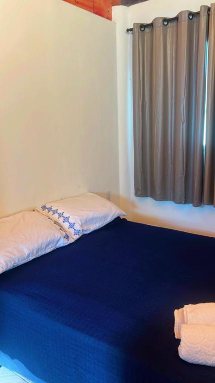 a bedroom with a blue bed with a window at chalé mares in Fortaleza