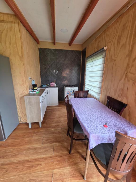 a dining room with a purple table and chairs at Cabaña Playa Chauquen in Neltume