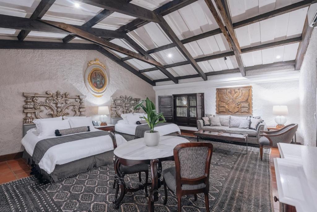a bedroom with two beds and a table and a couch at Las Cruces Boutique Hotel in Antigua Guatemala