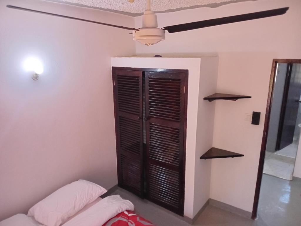 a room with a bed and a ceiling fan at Truenorth Apartments siem in Ukunda