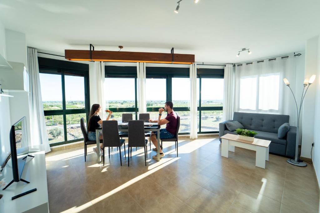 een groep mensen die aan een tafel in een woonkamer zitten bij Apartamento familiar en Torreblanca con vistas al mar, aire acondicionado y cerca de la playa in Torreblanca