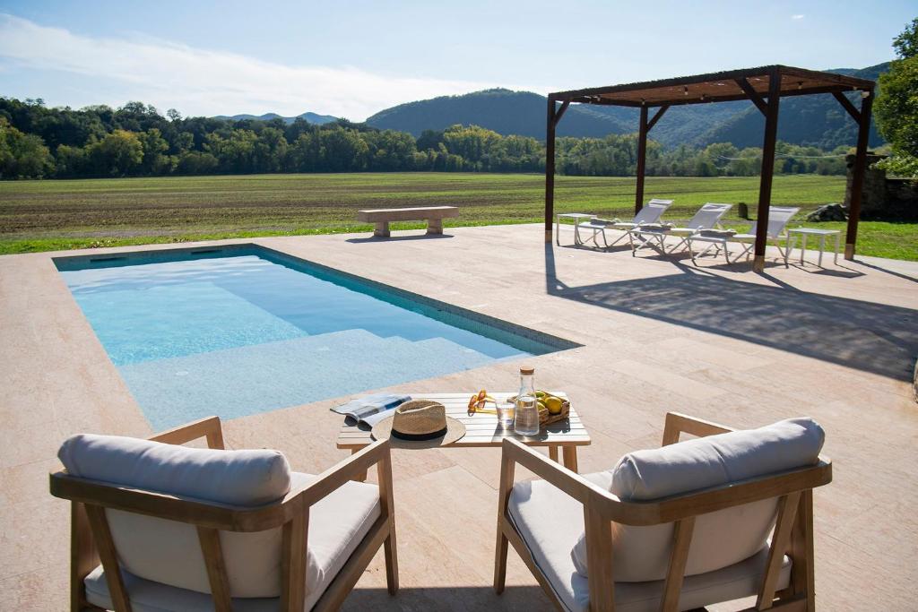 a patio with a table and chairs and a swimming pool at El Graner i El Niu in Sant Jaume de Llierca